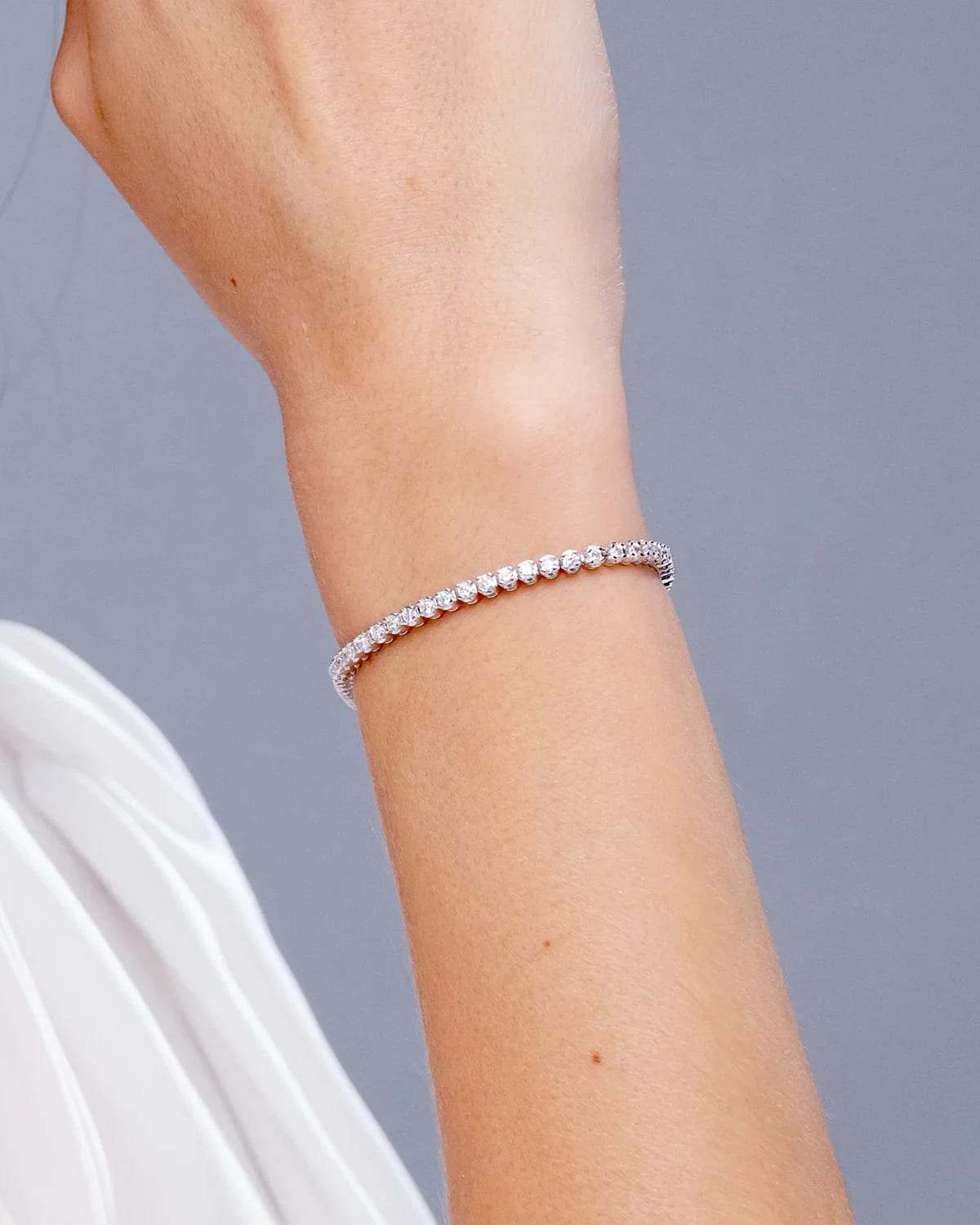A classic round diamond tennis bracelet worn on the wrist